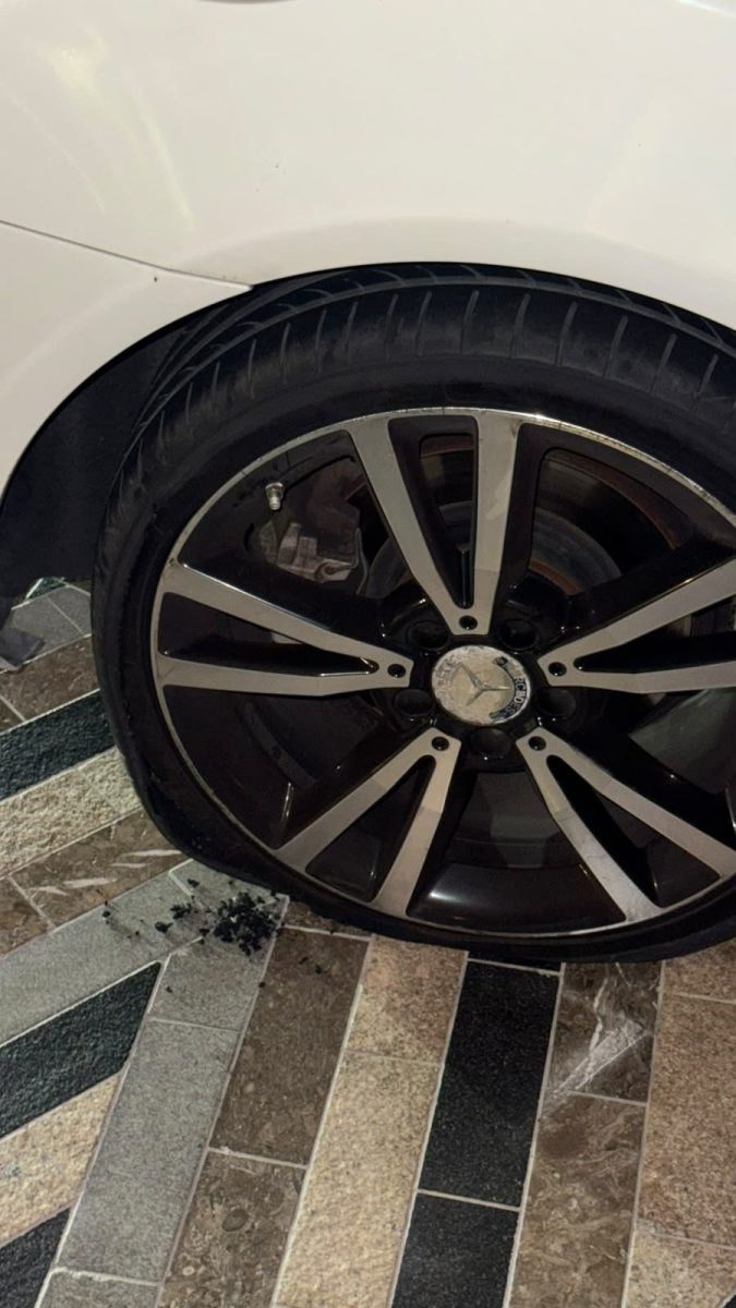 Flat tyre on a white Mercedes with the wheel resting on the ground